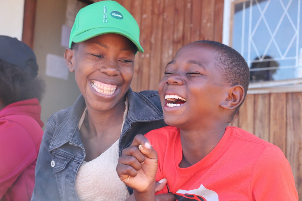 A mother and her son share a moment of laughter during a fortified food distribution programme in Zimbabwe – first-place photograph by Yeukai Kaponda