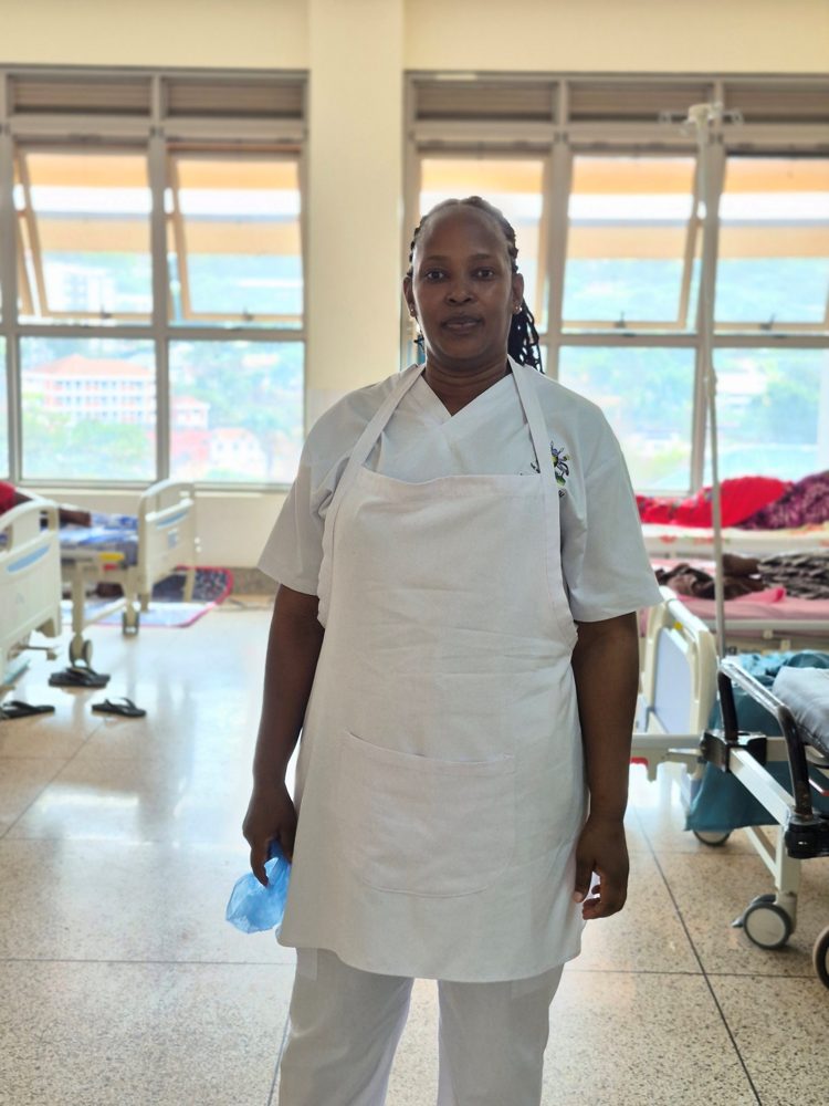 Sr. Asha, a senior nursing officer at Mulago National Referral Hospital's breast clinic, standing in a hospital ward