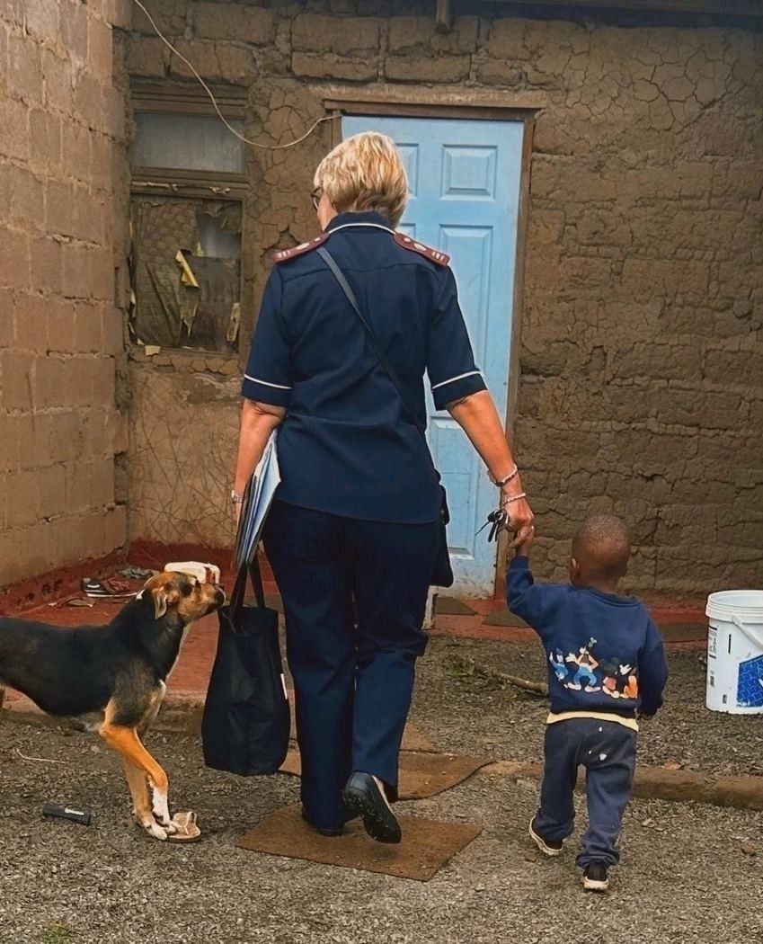 A nurse walks hand-in-hand with a child whose parent receives care.