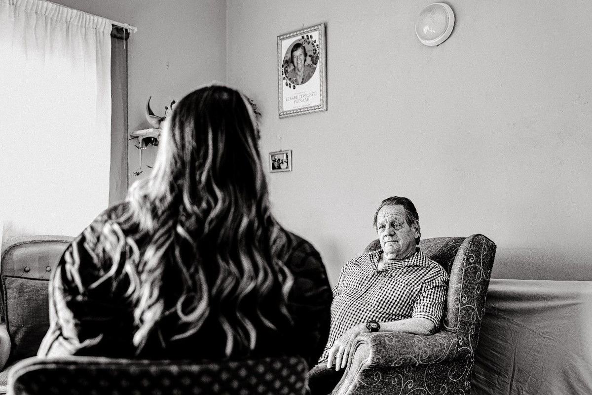 A social worker offers companionship and practical support during a widower's weekly home visit.