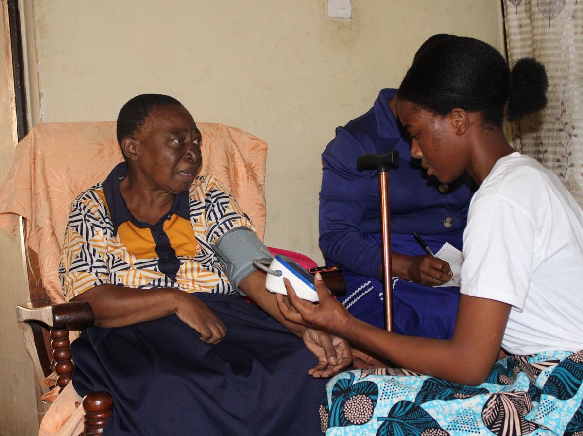 A care provider checks a woman's vital signs during a routine home visit.